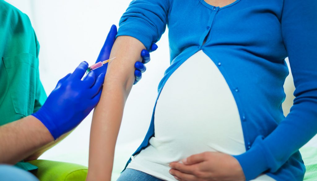 Doctor vaccinating young pregnant woman